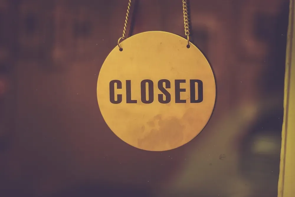 店铺玻璃门上挂着一块写着 CLOSED 的黄色圆牌