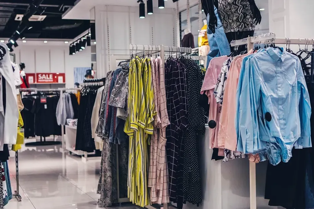 灯光明亮的服装店里挂满彩色女装的衣架