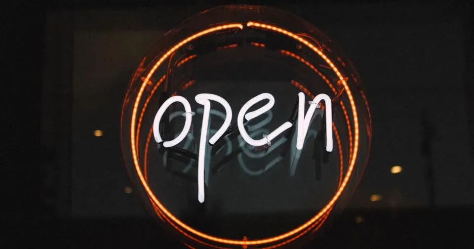 夜晚店铺玻璃窗后亮着的霓虹 open 招牌