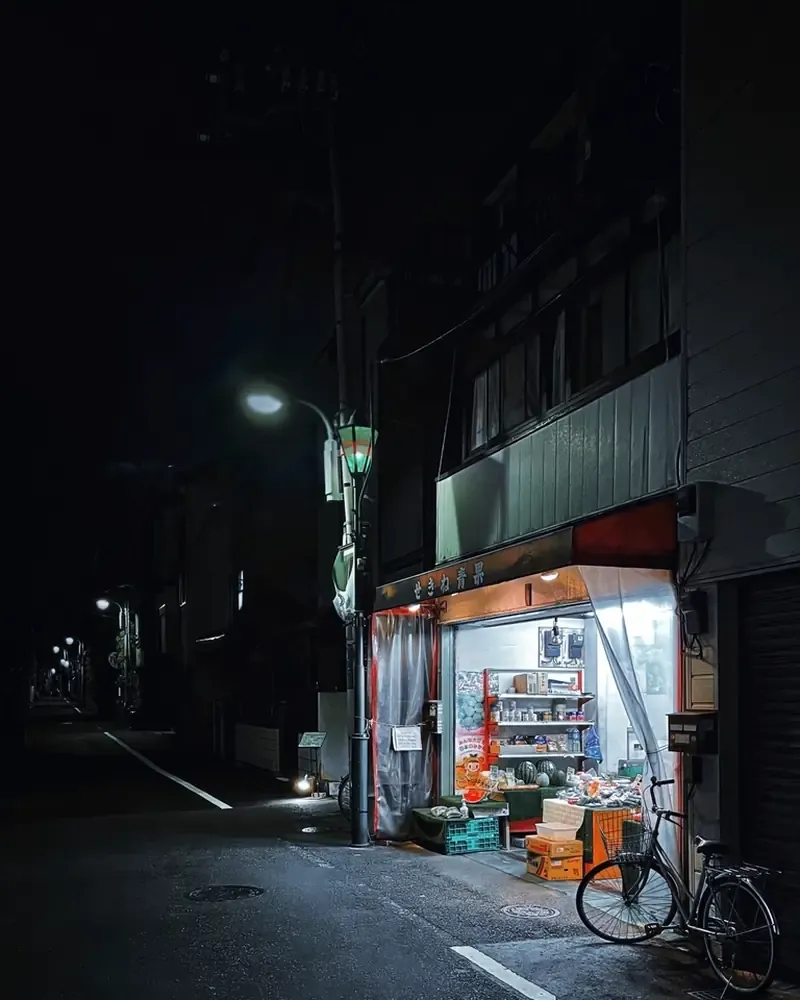 夜晚安静街角亮着灯的小店，门口停着一辆自行车